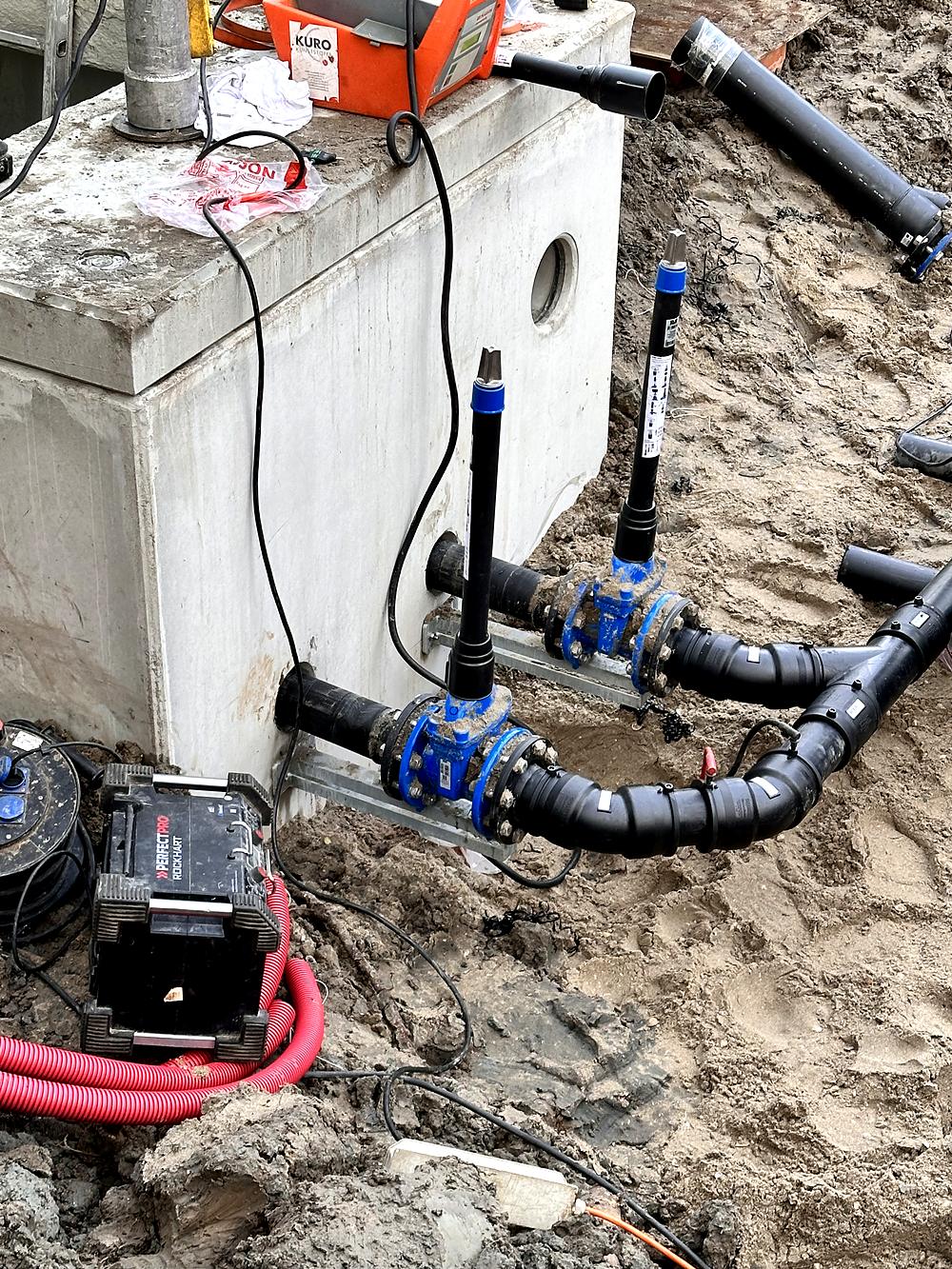 Leidingwerk met afsluiters naast een betonnen waterbouwkundige constructie